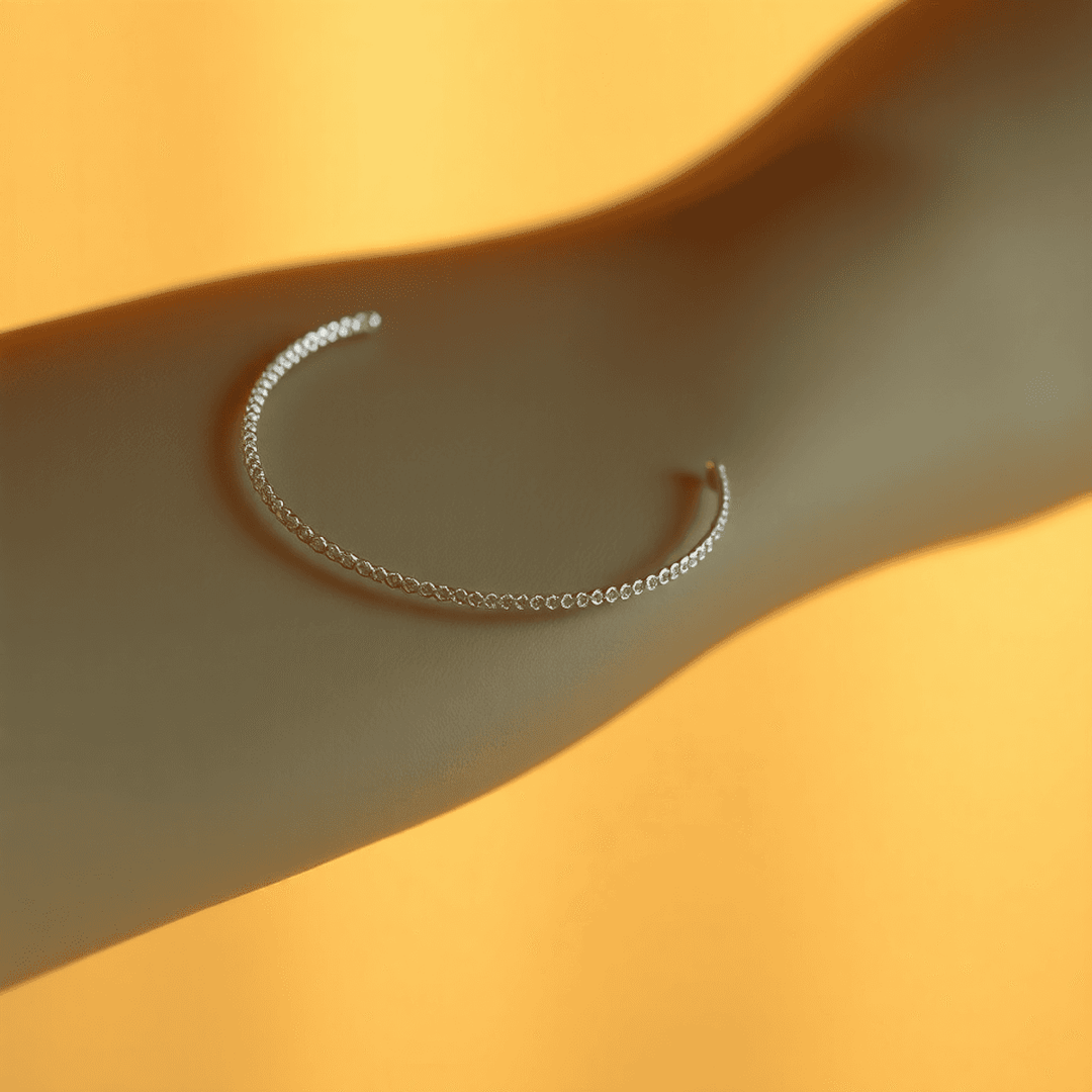 Close-up of a delicate silver bracelet glowing softly on a wrist against a warm, blurred background, symbolizing eternal connection and unbreakable bonds.